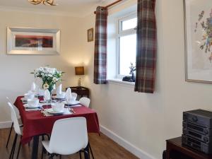 a dining room with a red table and white chairs at Glencairn Rd in Langbank