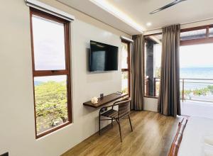 ein Zimmer mit Schreibtisch, Fernseher und Fenstern in der Unterkunft Seajour Beach Resort in Ginatilan