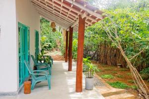 a patio with chairs and a wooden pergola at Lazy Monkey Green Chalets in Hiriketiya