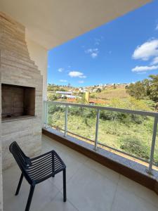 a room with a fireplace and a chair in front of a large window at Cobertura Duplex 301 espaçoso e com vista para as montanhas in São Lourenço