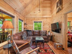 a living room with a leather couch and a television at The Three Dog Night Cabin in Bryson City