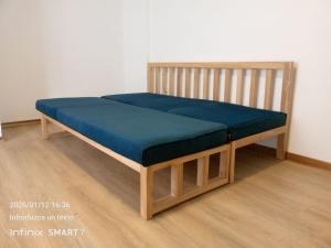 a wooden bed with a blue cushion on a wooden floor at Psi Nova in Baños