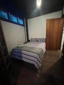 a small bed in a room with a wooden door at Suite casa cachoeira in Paraty