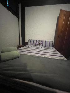 a bed with a striped pillow in a room at Suite casa cachoeira in Paraty +5 photos