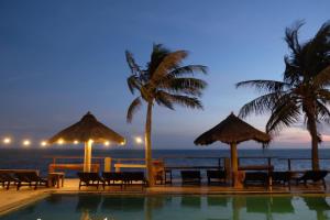 a swimming pool next to the beach at night at Viva Beach Resort Mui Ne in Mui Ne