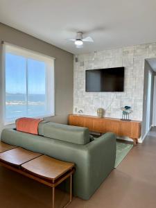 a living room with a couch and a tv at Guarapari Center Aparts in Guarapari