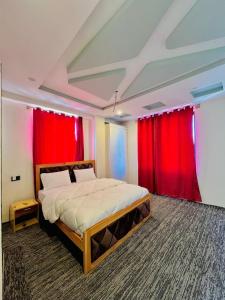 ein Schlafzimmer mit einem großen Bett und roten Vorhängen in der Unterkunft Fialong Hotel Skardu in Skardu + 25 Fotos