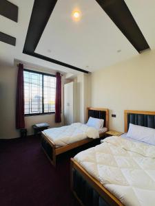 ein Zimmer mit zwei Betten und einem Fenster in der Unterkunft Fialong Hotel Skardu in Skardu