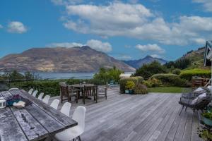 a wooden deck with a table and chairs and a lake at Ora Retreat in Queenstown