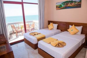 two beds in a room with a view of the ocean at Viva Beach Resort Mui Ne in Mui Ne