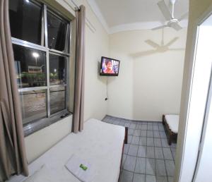 a room with a tv and a window at Estação Pousada e Hostel in Cataguases