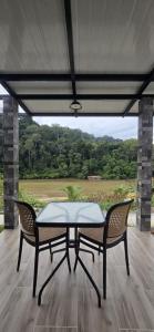 a table and two chairs on a porch with a view at TEBiNG Guest House Taman Negara Malaysia Kuala Tahan in Kuala Tahan