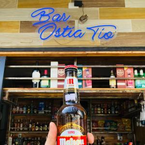 a person holding a bottle of beer in front of a store at Preciosa Suite Familiar para 10 personas con cocina y 3 piscinas in Playas