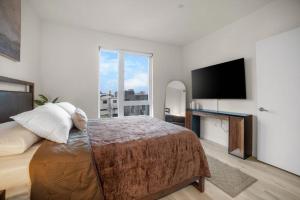 a bedroom with a large bed and a flat screen tv at Modern Lux Midrise Stadium & Downtown Views in West Sacramento