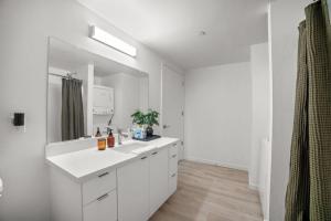 a white bathroom with a sink and a mirror at Modern Lux Midrise Stadium & Downtown Views in West Sacramento