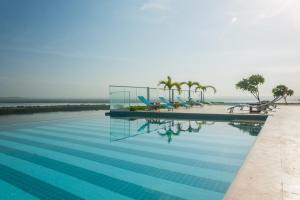 a swimming pool with chairs and the ocean in the background at Luxury Ocean View Aparment in Cartagena de Indias