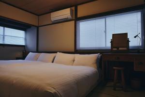 a bedroom with a large bed and two windows at 白金はなれ in Susakiuramachi