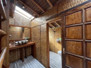 a bathroom with a wooden door and a toilet at Floating Paradise in Karimunjawa