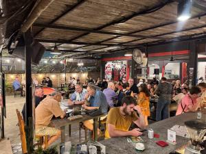 a group of people sitting at tables in a restaurant at Pomme Brewhouse Hostel in Siem Reap