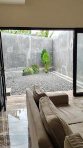a living room with a couch in front of a window at patangpuluh homestay in Purwokerto