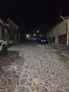 a cobblestone street at night with cars parked on it at The Stone Way Suite in Juayúa