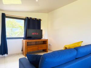 a living room with a blue couch and a tv at Quiet house - great mountain view in Tiaraha