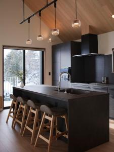 a kitchen with a large island with bar stools at Villa Matsu by H2 Life in Nakafurano