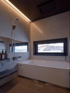a bathroom with a bath tub and a window at Villa Matsu by H2 Life in Nakafurano +12 photos