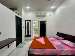 a bedroom with a bed with pink sheets and a table at Nana's Residency, Cochin in Alwaye