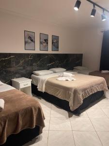 two beds in a room with three pictures on the wall at Pousada Bon Vivant in Cabo Frio +214 photos