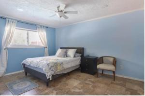 a bedroom with a bed with a ceiling fan and a chair at Cozy Room with a Pool in Houston