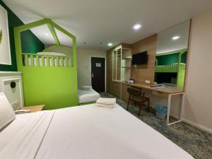 a bedroom with a white bed and a desk and a green wall at Asto Hotel Kuala Lumpur in Kuala Lumpur