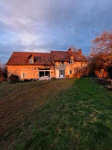 a large brick house with a grass field in front of it at maison la Bambine chambre esprit château in Ozolles