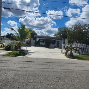 a house with a white fence and palm trees at Private and beautiful room for vacation in Carver Ranches