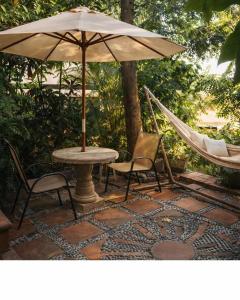 a hammock and a table and chairs with an umbrella at La Casa del Guamúchil in Tequesquitengo