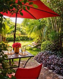 a table with a red umbrella in a garden at La Casa del Guamúchil in Tequesquitengo