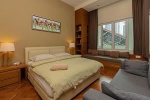 a bedroom with a bed and a couch and a window at SQSu in Tanjong Tokong
