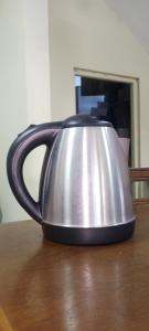a metal tea kettle sitting on a wooden table at RooLi Harbour Inn-Trincomalee in Trincomalee
