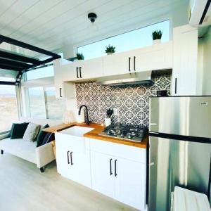 a kitchen with white cabinets and a refrigerator at Joshua Tree Tiny Home - Remote & Modern Container Home on 5 Acres in Joshua Tree
