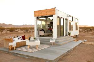 a house in the desert with a couch and a table at Joshua Tree Tiny Home - Remote & Modern Container Home on 5 Acres in Joshua Tree +14 photos