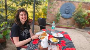 a woman sitting at a table with a plate of food at Marari Sabari Home Stay in Mararikulam