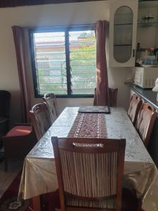 a dining room table with a chair and a window at Stay with Sheena - Homestay Experience in Nadi