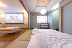 a room with two beds and a projection screen at Tabiudo Souwa in Takayama