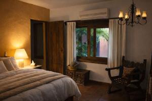 a bedroom with a bed and a chair and a window at La Casa del Guamúchil in Tequesquitengo