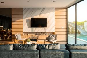 a living room with a couch and a tv at The Moon Huahin Pool Villa in Hua Hin
