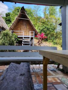 a bench sitting in front of a thatch hut at Bon Joy's Transient House in Mabini