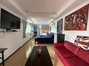 a living room with a red couch and a tv at TopCats Fishing Resort in Taling Ngam Beach