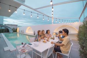 a group of people sitting at a table on a patio at The Moon Huahin Pool Villa in Hua Hin