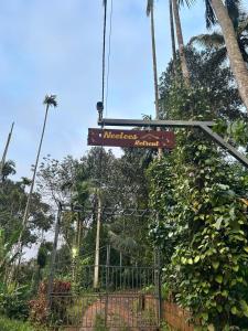 a sign hanging from a fence at a zoo at Neelees Retreat in Kaniyāmbetta