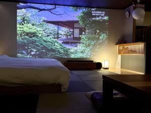 a bedroom with a bed and a large window with trees at Tsuzumi Suite - Private Cinema & Immersive Stay in Kanazawa in Housai